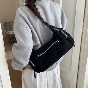 Detail of minimalist black matte crossbody bag with silver zipper and long leather puller