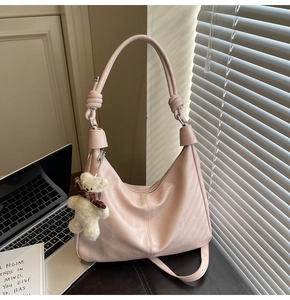 Detail of pink dumpling tote bag with soft leather texture and cute plush bear charm