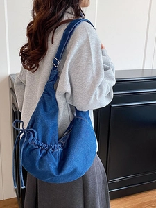 Chic dark blue denim crescent crossbody bag with side drawstring bows and adjustable strap