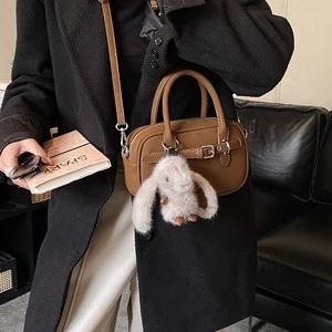Detail of vintage brown leather handbag with plush rabbit charm and adjustable strap