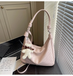 Pink minimalist crescent shoulder bag featuring knot strap detail and plush bear charm