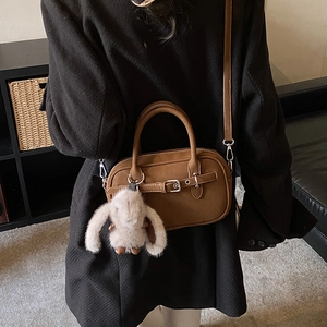 Detail of vintage brown leather bag with buckle decor and cute white rabbit charm