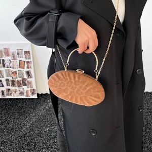Detail of a brown pleated evening bag with gold handle and crystal buckle closure