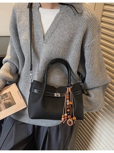 Retro black leather tote bag with metallic lock and ethnic bead pendant on top handle