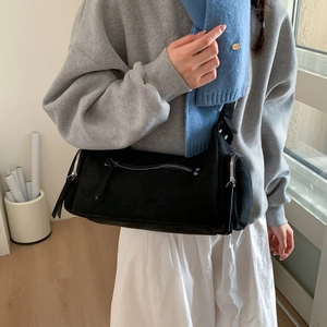 Detail showing the black suede cylindrical bag with stylish silver metal zippers