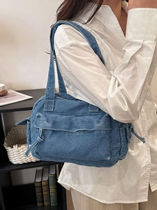 Minimalist denim tote bag with external pockets and drawstring detail shown on model