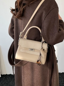 Versatile beige crossbody bag with herringbone weave flap and heart-shaped pendant detail