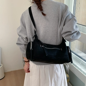 Detail of black suede dumpling bag featuring multiple zippers and wide shoulder strap