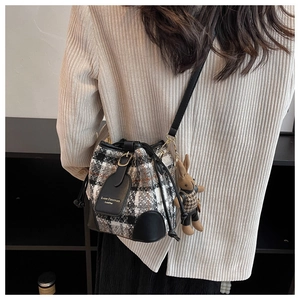 Détail du sac seau à carreaux avec garniture en cuir noir et charmant pendentif en peluche