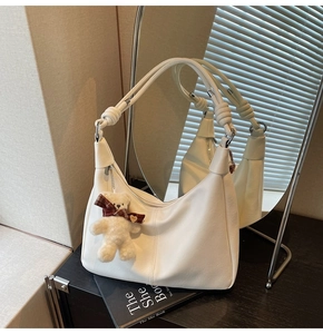 Detail of white Hobo bag with leather knots and a cute plush bear charm accessory