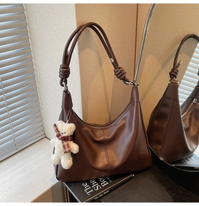Detail of vintage brown PU leather hobo bag with a knot strap and plush bear charm