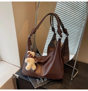 Detail of soft dark brown leather hobo bag with knot strap and plush bear charm