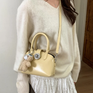 Retro yellow crossbody handbag with silver turn-lock and brown teddy bear charm accessory