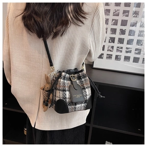 Vue détaillée d'un sac seau en tweed à carreaux avec finitions en cuir noir et breloque lapin
