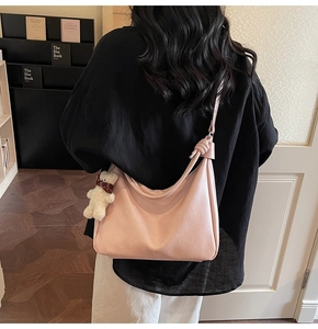 Detail of pink lychee leather tote bag with knot strap and teddy bear charm accessory
