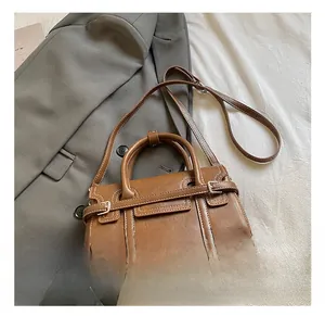 Detail of vintage brown leather handbag with contrast stitching on grey blazer background