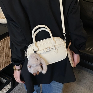 Detail of cream Boston bag featuring silver buckle decor and cute plush rabbit charm