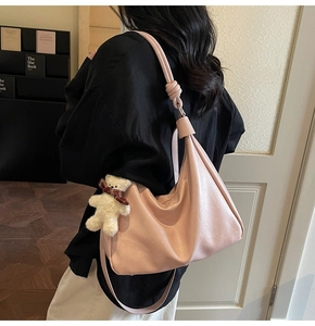 Detail shot of pink oversized shoulder bag with knotted strap and teddy bear charm