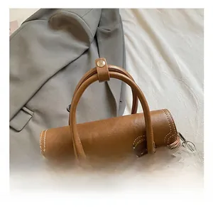 Detailed view of brown faux leather handbag with white contrast stitching and metal hardware
