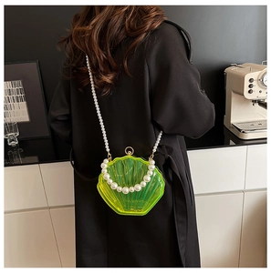 Detail of neon green shell-shaped acrylic bag with pearl chain shown on black coat