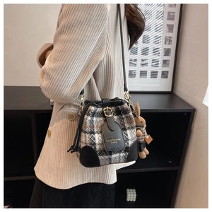 Détail d'un sac seau à carreaux avec rabat en cuir et breloque lapin en peluche
