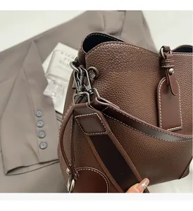Detail of dark brown lychee grain leather handbag with contrast stitching and metal hardware