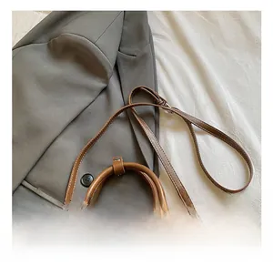 Detail of adjustable leather shoulder strap and fine white stitching on a brown handbag