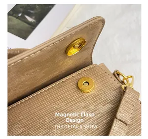 Detail of the golden magnetic closure and textured beige leather on a small square bag