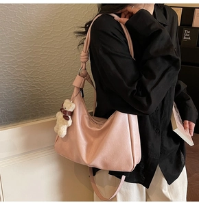 Detail of pink hobo shoulder bag with soft PU leather texture and plush bear charm