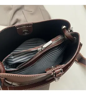Detailed interior of brown pebbled leather bucket bag with striped lining and silver zipper