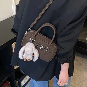 Detail of dark brown vintage Boston bag featuring belt buckle and plush rabbit charm