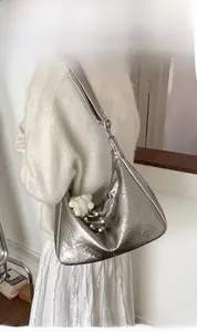 Détail d'un sac à bandoulière argenté plissé avec breloque en peluche et perles en bois