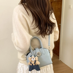 Detail of light blue patent leather handbag with silver lock and plush bear charm