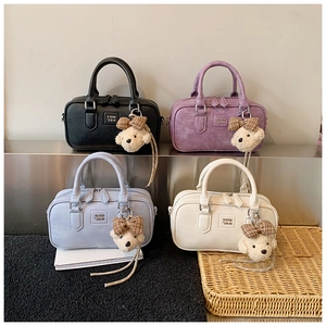 Detail of four colorful Boston bags with teddy bear charms on a tiered display
