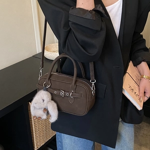 Detail view of dark brown Boston bag featuring vintage silver buckle and plush rabbit charm