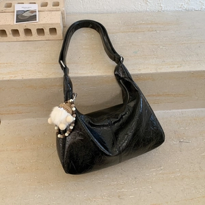 Détail du sac à épaule en cuir verni plissé noir avec un pendentif en peluche blanc