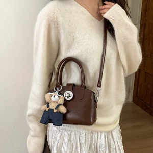 Detail of vintage dark brown handbag with silver clasp and cute plush bear accessory