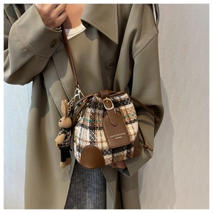 Détail d'un sac seau en tweed à carreaux avec garniture en cuir et breloque lapin