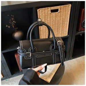 Detail of black handbag with white contrast stitching and vintage belt buckle decorative