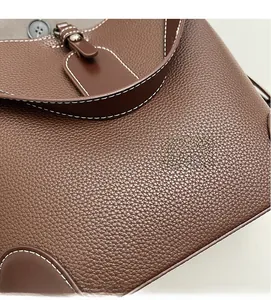 Close-up of brown litchi grain leather texture and contrasting white stitching detail