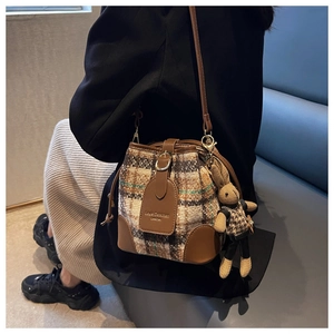 Détail du sac seau à carreaux vintage avec rabat en cuir brun et breloque lapin