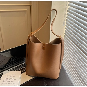 Macro detail of camel lychee leather bucket bag with a golden metal rotary twist lock closure