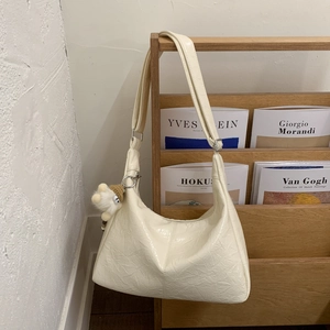 Détail du sac hobo en cuir verni blanc cassé avec pendentif en forme de boule en peluche