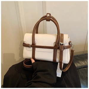 Detailed close-up of the adjustable brown shoulder strap and buckle on the beige handbag
