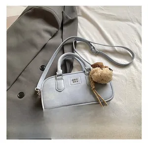 Close-up of a light blue mini Boston bag with a teddy bear charm and metal logo