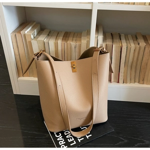 Detail of beige bucket bag with gold metal clasp on lychee grain leather texture