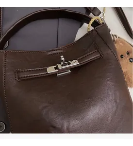 Close-up of silver twist lock and pebble grain leather on a dark brown bucket bag