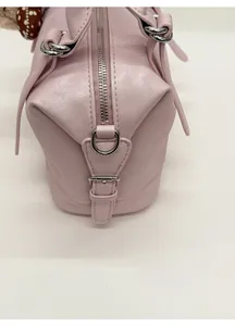 Detail view of pink leather tote bag showing silver metal zipper and buckle on the side