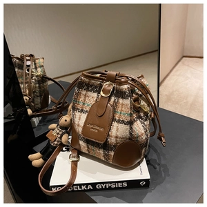 Détail du sac seau en tweed avec base en cuir et charmant ours en peluche à carreaux