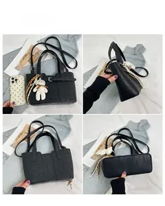 Detail view of black leather bucket bag with plush bear charm and striped silk ribbon